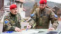 Zwei Soldaten an einem Fahrzeug, die sich eine Lagekarte angucken