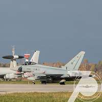 Ein großes AWACS-Aufklärungsflugzeug fährt hinter einem Eurofighter-Kampfjet auf der Air Base Ämari.