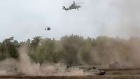 Unterschiedliche Gefechtsfahrzeuge und Hubschrauber während der militärischen Operation