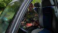 Ein Soldat sitzt mit einer künstlichen Wunde und Kunstblut in einem Autowrack.