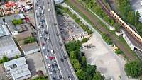 Vogelperspektive auf einen Autobahnabschnitt in grüner Umgebung. Auf der Autobahn fahren Fahrzeuge