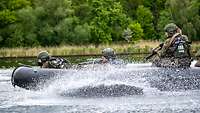 Soldaten fahren mit hoher Geschwindigkeit in einem Schlauboot auf einem Fluss