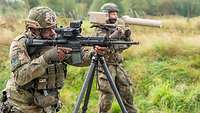 Zwei Soldaten stehen mit Sturmgewehr und Störsender im Gelände.