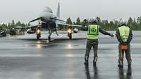 Crew Chief und Bodenpersonal dirigieren Eurofighter im Regen