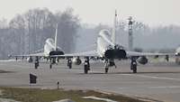 Zwei Eurofighter stehen hintereinander auf der Flugplatzplatte