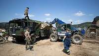 Ein Radlader des THW belädt einen militärischen Lkw