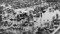 Ein Hubschrauber der Bundeswehr fliegt über überflutete Stadteile von Hamburg