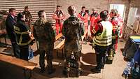 In einem Kreis besprechen sich Soldaten, Feuerwehrleute und Sanitäter