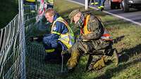 Ein Soldat und ein THW-Mitarbeiter errichten einen provisorischen Schutzzaun