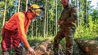 Ein Soldat und ein Zivilist im Wald untersuchen einen Baumstamm am Boden