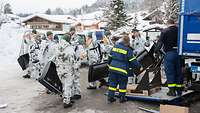 Eine große Anzahl von Soldaten empfängt Schneeschaufeln von einem THW-Mitarbeiter an einem Lkw