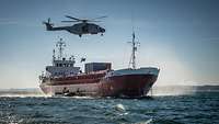 Ein Kampfschwimmer der Bundeswehr seilt sich aus einem Hubschrauber auf ein ziviles Frachtschiff ab
