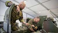 2 Soldaten in Uniform arbeiten an einem Militärfahrzeug