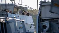 Mehrere Soldaten stehen auf einem Schiff, während sie den Hafen verlassen