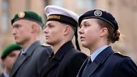 Eine Soldatin und zwei Soldaten unterschiedlicher Streitkräfte stehen nebeneinander.