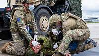 Zwei belgische Soldaten versorgen einen estnischen Soldaten, der bei einer Übung einen Verwundeten spielt