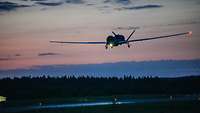 Ein unbemanntes Luftfahrzeug der NATO RQ-4D Phoenix im Anflug auf die Landebahn bei Dunkelheit.