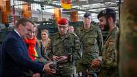 Ein Zivilist und mehrer Soldaten gucken sich eine Drohne an.