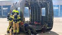 Zwei Feuerwehrmänner schauen durch ein Fenster eines Hubschrauberrumpft auf die verletzten Personen.