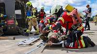 Feuerwehrleute retten eine verletzte Person aus dem Hubschrauberrumpf.