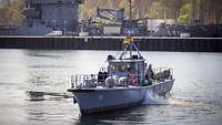 Ein Boot der Marine fährt auf einem Gewässer im Hafen.