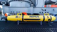 Eine Unterwasserdrohne mit der Aufschrift „REMUS“ liegt an Bord eines Minenjagdbootes.
