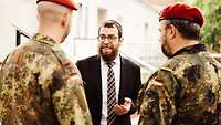 Ein Rabbiner mit Kippa ist von Soldaten umringt.