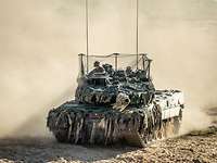 Kampfpanzer mit Fangnetz über dem Turm.