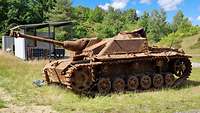 Ein alter, verrosteter Panzer steht im Gelände.