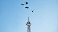 Vier Kampfflugzeuge fliegen über den Berliner Funkturm.