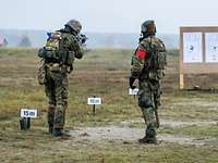 Ein ukrainischer Soldat schießt auf eine Schützenscheibe. Neben ihm steht ein deutscher Soldat.