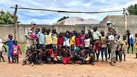Ein Gruppenfoto mit Kindern aus dem Südsudan und zwei UN Beobachterinnern vor einem Fußballtor
