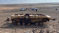 Zwei geparkte UN-Fahrzeuge von Militärbeobachtern in der Westsahara vor einem zerstörten Panzer