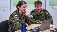 Eine polnische Soldatin und ein deutscher Soldat sitzen an einem Laptop.