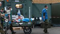 Soldaten in medizinischer Kleidung schieben einen Verletzten auf einer Trage