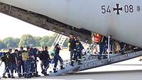 Einsatzkräfte des THW steigen über die Heckrampe an Board eins A400M der Luftwaffe.