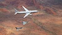Zwei deutsche Eurofighter und ein Flugzeug in der Luft.