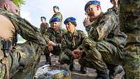 Ein Soldat erklärt den Inhalt eines Rucksacks, weitere Soldaten schauen dabei zu.