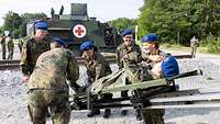 Eine Gruppe Soldaten zieht eine Trage mit einem Soldaten aus einem Fahrzeug.