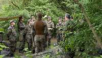 Soldatinnen und Soldaten in einem Wald, ein Soldat erklärt etwas