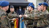Eine Gruppe Soldaten hält jeweils eine Hand über eine Fahne