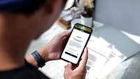 Ein junger Mann füllt mit seinem Smartphone einen Fragebogen aus.