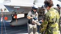 Vier Soldaten stehen vor einem Flugzeug. Eine Soldatin hält einen Schlauch in der Hand.