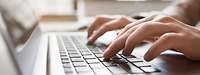 Eine Person nutzt die Tastatur eines Laptops