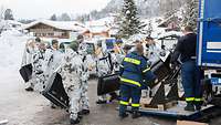 Numerous soldiers receiving snow shovels from an employee of the Federal Agency for Technical Relief