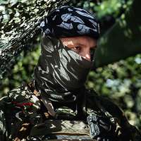 Portrait eines Soldaten, der unter einem Tarnnetzt steht.