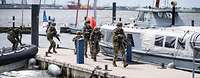 Bewaffnete Soldaten steigen aus einem Schlauchboot aus und laufen einen Bootssteg entlang.