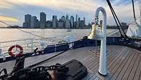Die Schiffsglocke an Deck des Segelschulschiffs Gorch Fock vor der Skyline von New York