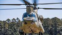 Ein Hubschrauber mit Tandemrotoren fliegt auf den Betrachter zu.