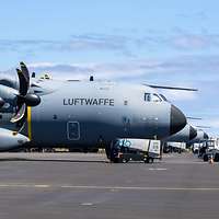 Mehrere Transportflugzeuge stehen in einer Reihe auf dem Rollfeld.